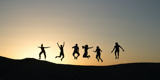 6 Menschen springen auf einem Berg beim Sonnenuntergang